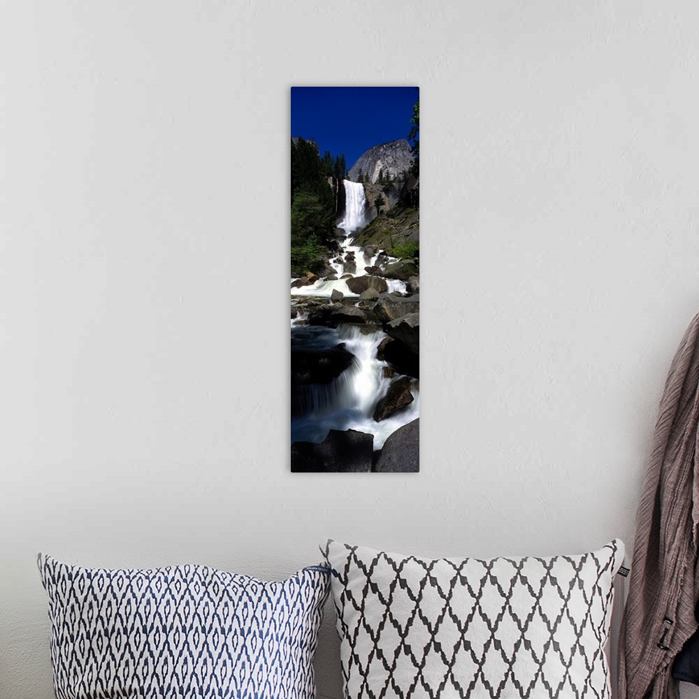 A bohemian room featuring Vertical panoramic photograph of waterfall flowing into a rocky stream surrounded by trees.