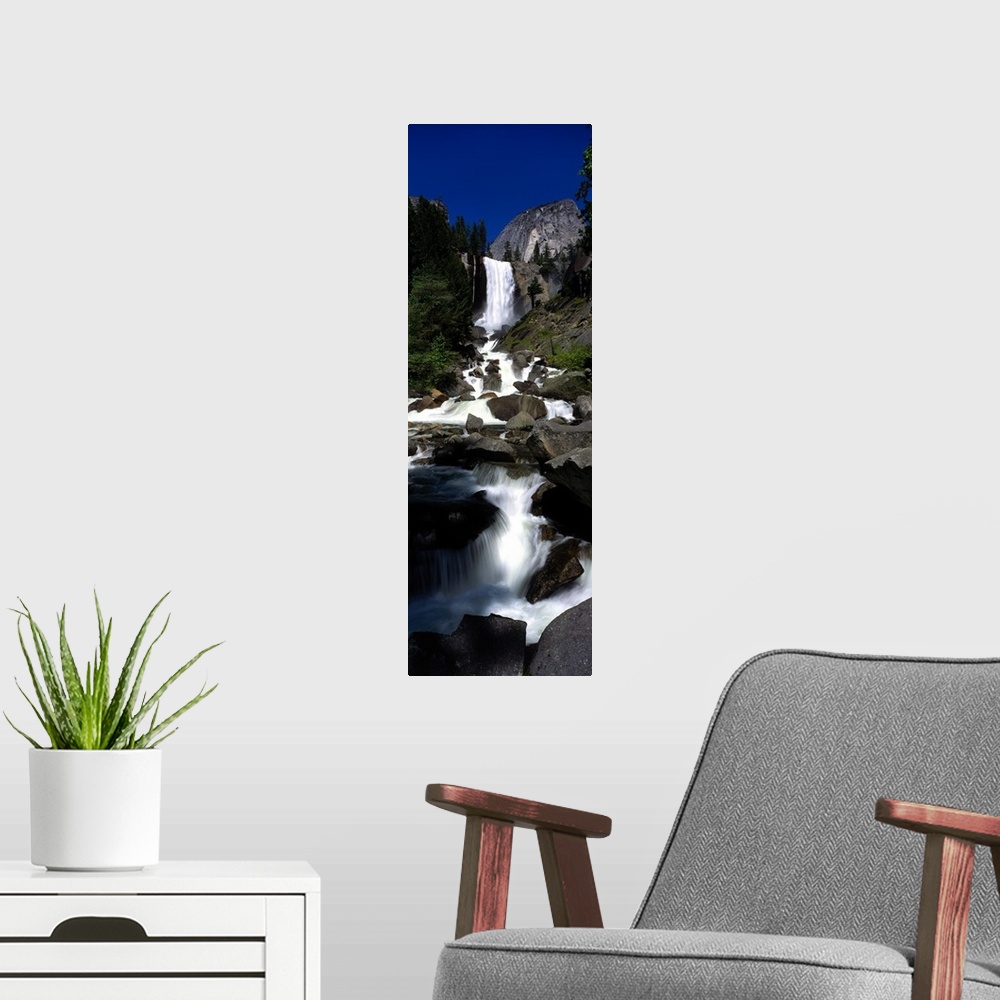 A modern room featuring Vertical panoramic photograph of waterfall flowing into a rocky stream surrounded by trees.