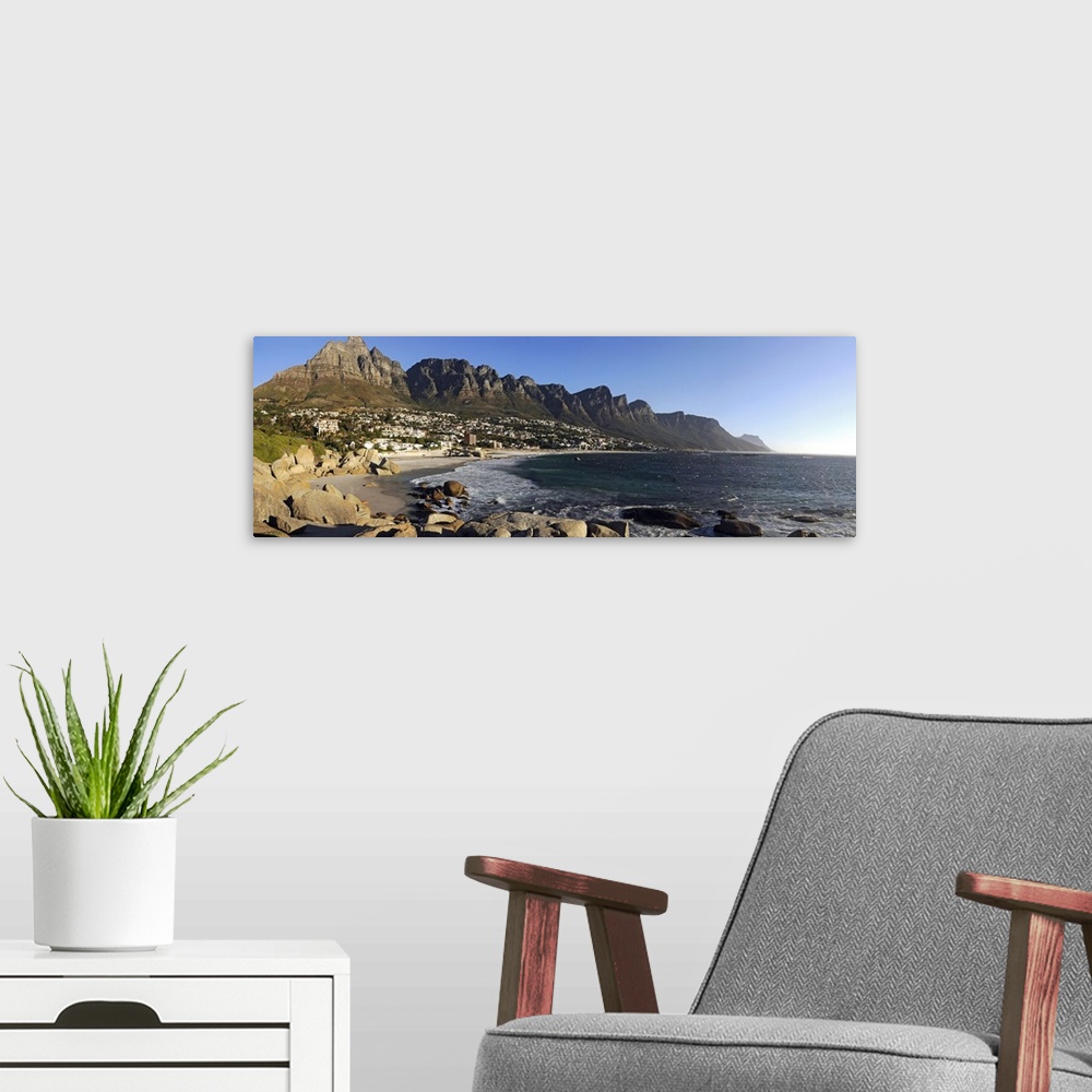 A modern room featuring Panoramic photograph of shoreline with rocky cliffs and huge rock formations under a clear sky.