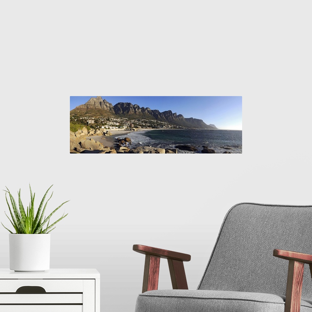 A modern room featuring Panoramic photograph of shoreline with rocky cliffs and huge rock formations under a clear sky.