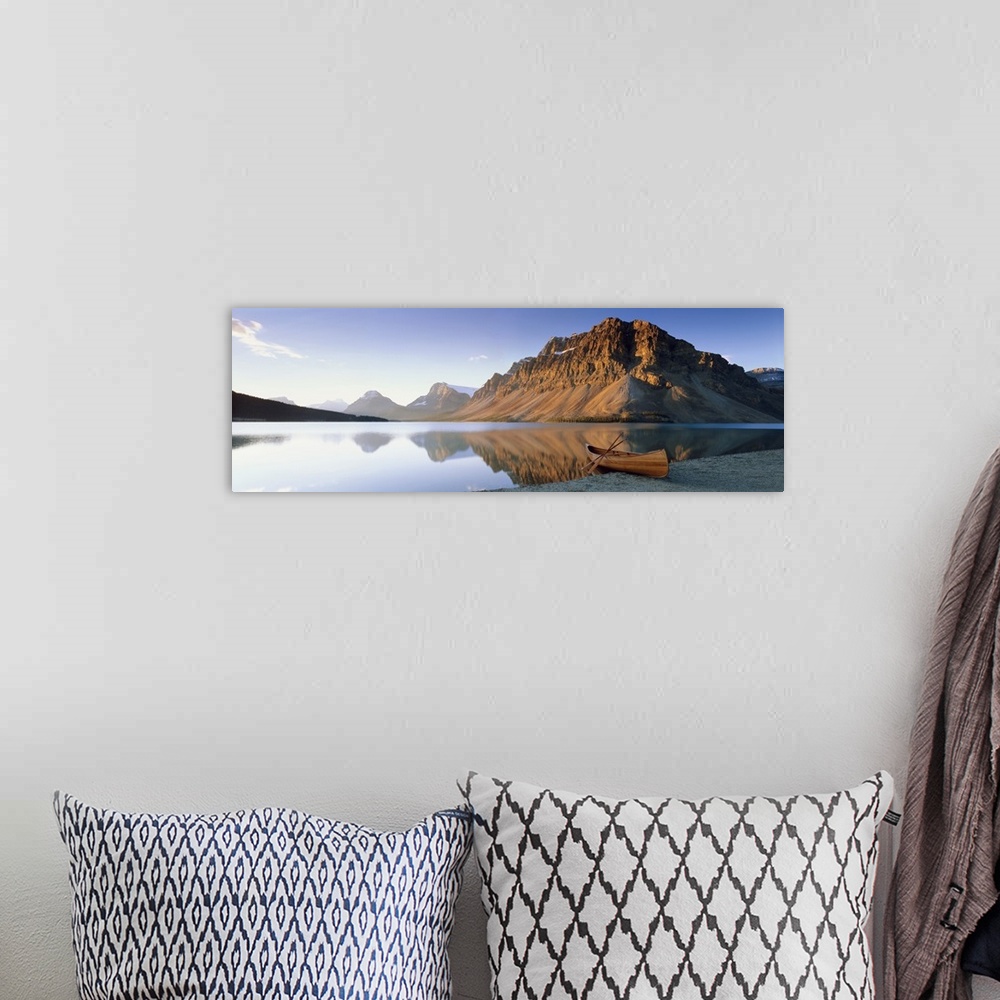 A bohemian room featuring Panoramic photo on canvas of a smooth lake with a wooden canoe on the shoreline and big rocky mou...