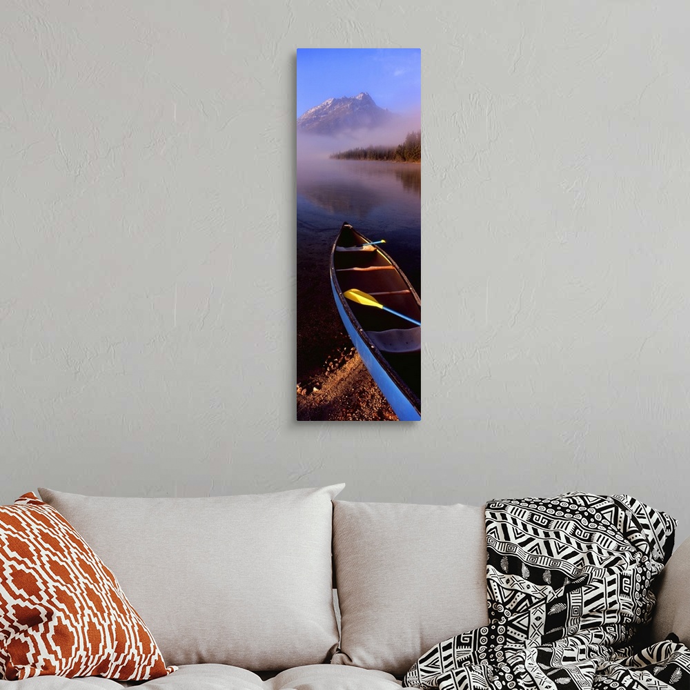 A bohemian room featuring Tall and narrow canvas photo of a canoe half way in a lake with fog in the distance in front of a...