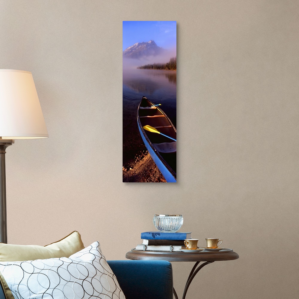A traditional room featuring Tall and narrow canvas photo of a canoe half way in a lake with fog in the distance in front of a...