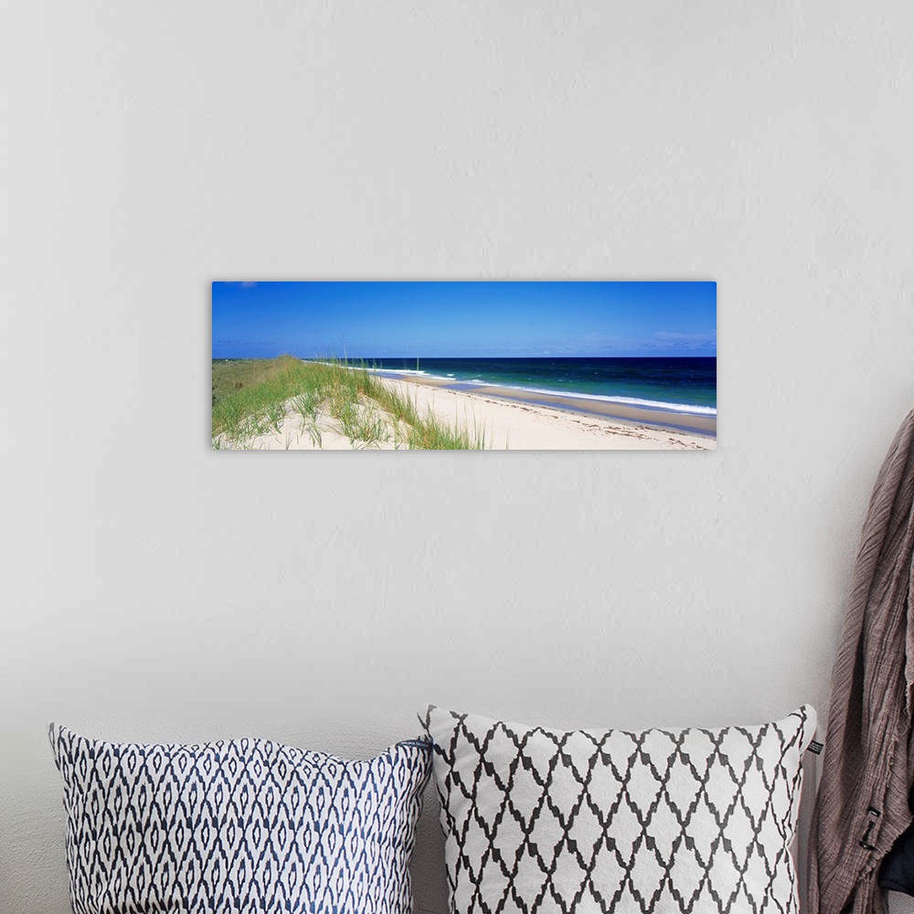 A bohemian room featuring Panoramic photograph focuses on a long stretch of a sandy beach within North Carolina as the wave...