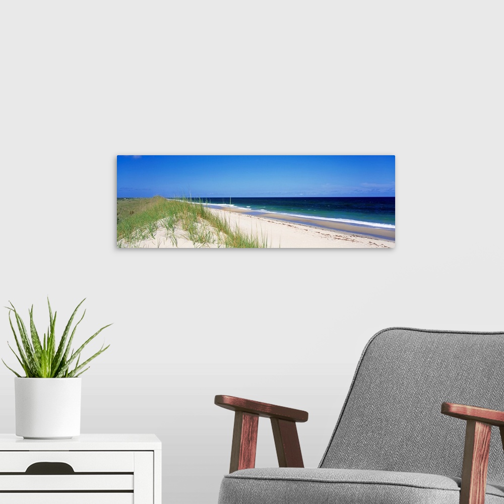 A modern room featuring Panoramic photograph focuses on a long stretch of a sandy beach within North Carolina as the wave...