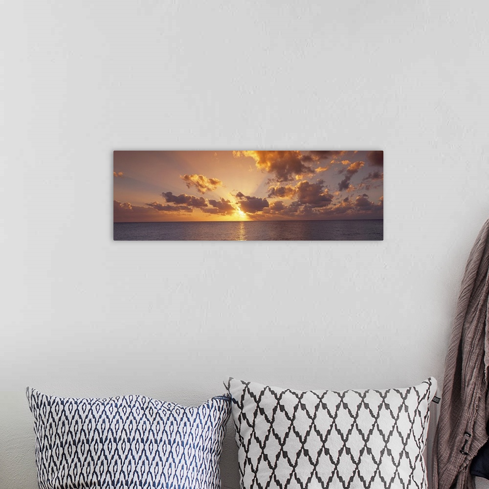 A bohemian room featuring Wide angle photograph of the setting suns rays beaming through a partly cloudy sky and reflecting...