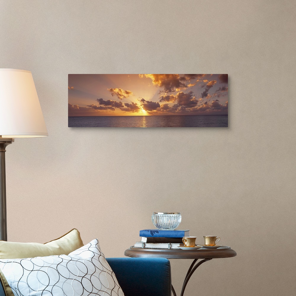 A traditional room featuring Wide angle photograph of the setting suns rays beaming through a partly cloudy sky and reflecting...