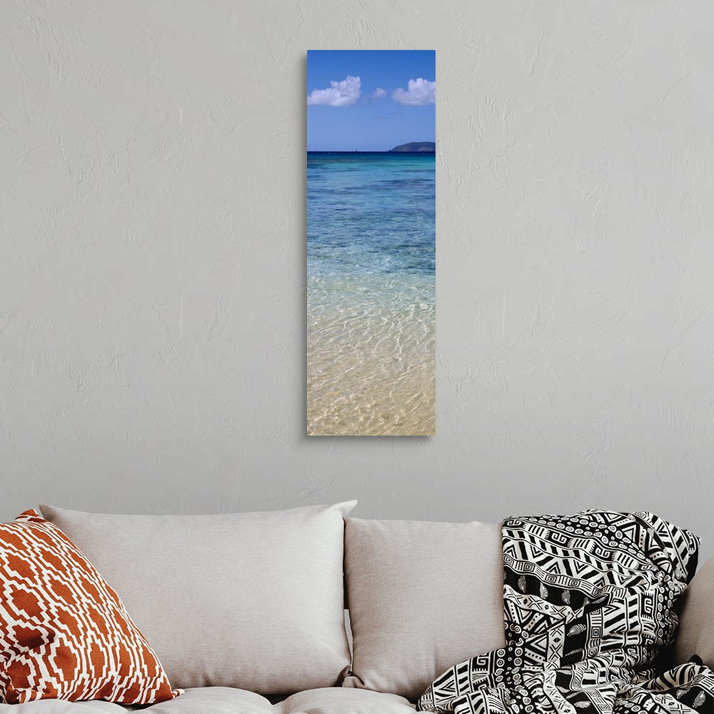 A bohemian room featuring Tall and narrow canvas print of clear Caribbean ocean water with a mountain in the distance.