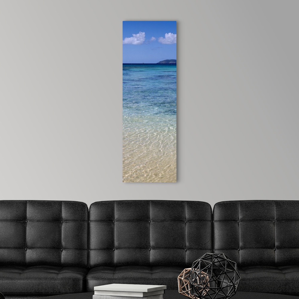 A modern room featuring Tall and narrow canvas print of clear Caribbean ocean water with a mountain in the distance.