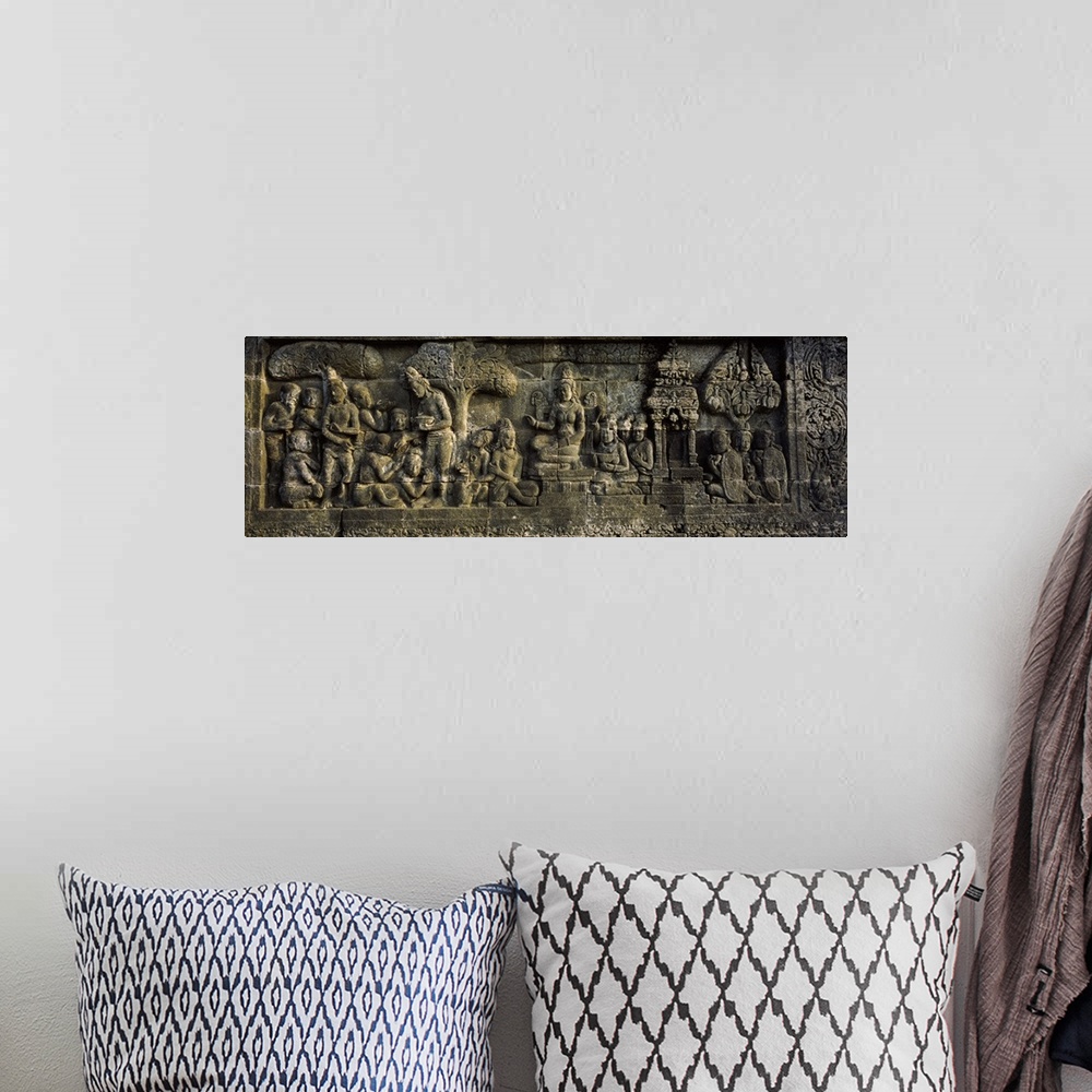 A bohemian room featuring This elongated piece is of a stone wall that has had artwork carved into it.