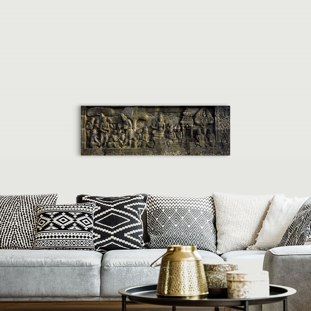 A bohemian room featuring This elongated piece is of a stone wall that has had artwork carved into it.