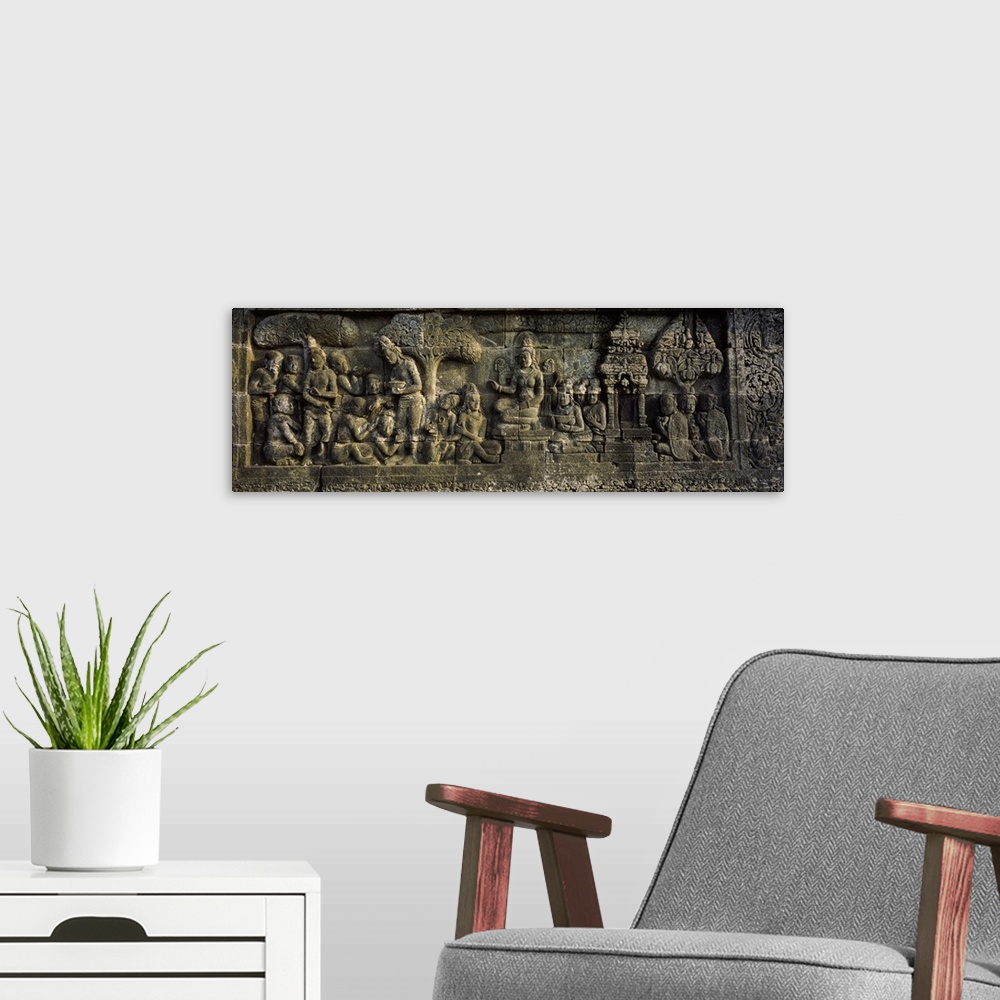 A modern room featuring This elongated piece is of a stone wall that has had artwork carved into it.
