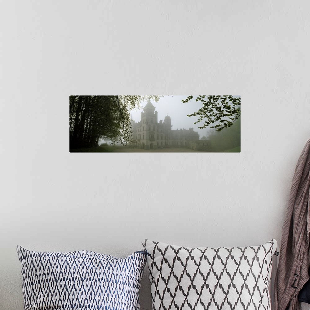 A bohemian room featuring A large castle is faintly shown behind fog and surrounded by trees.
