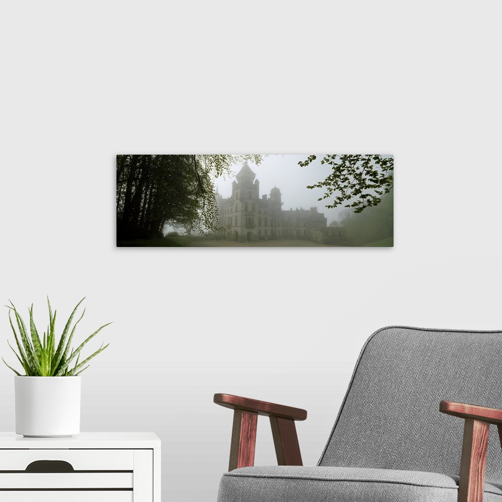 A modern room featuring A large castle is faintly shown behind fog and surrounded by trees.