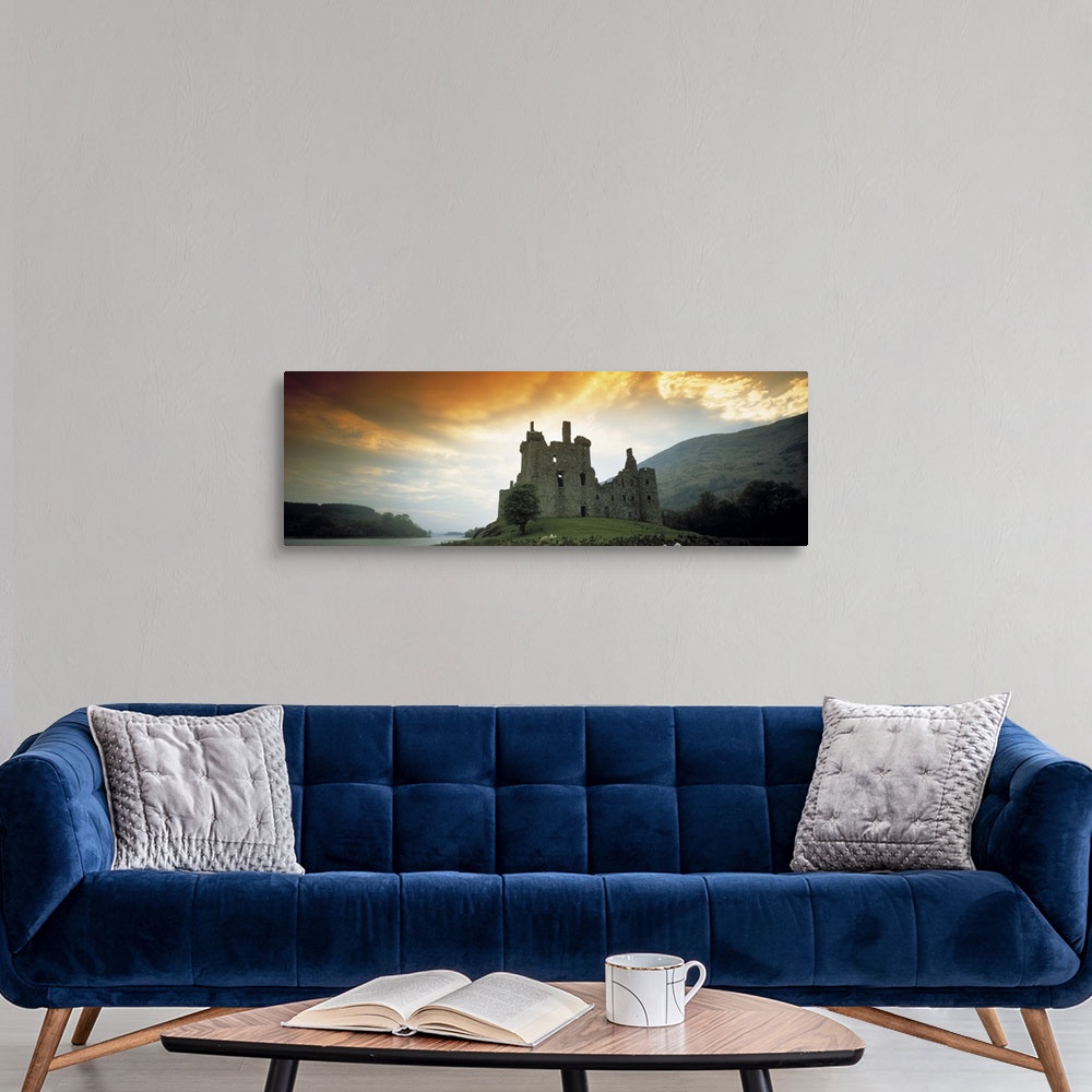 A modern room featuring Panoramic photograph of stone palace on hillside at sunset.  There is water in the distance and t...