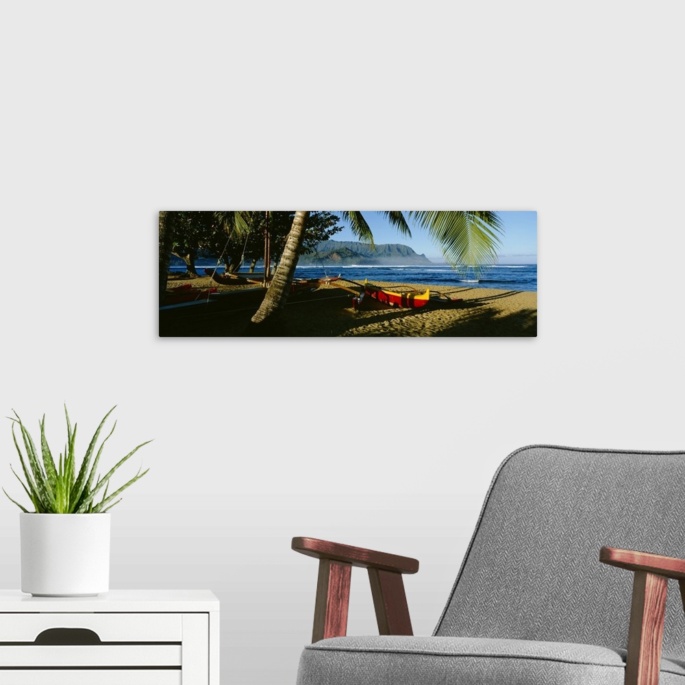 A modern room featuring A large panoramic photograph of a boat on the beach that is mostly covered by the shadows of palm...