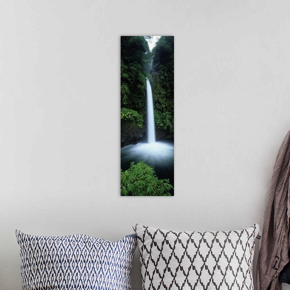 A bohemian room featuring Vertical canvas print of a narrow but powerful waterfall rushing down from a tropical forest.