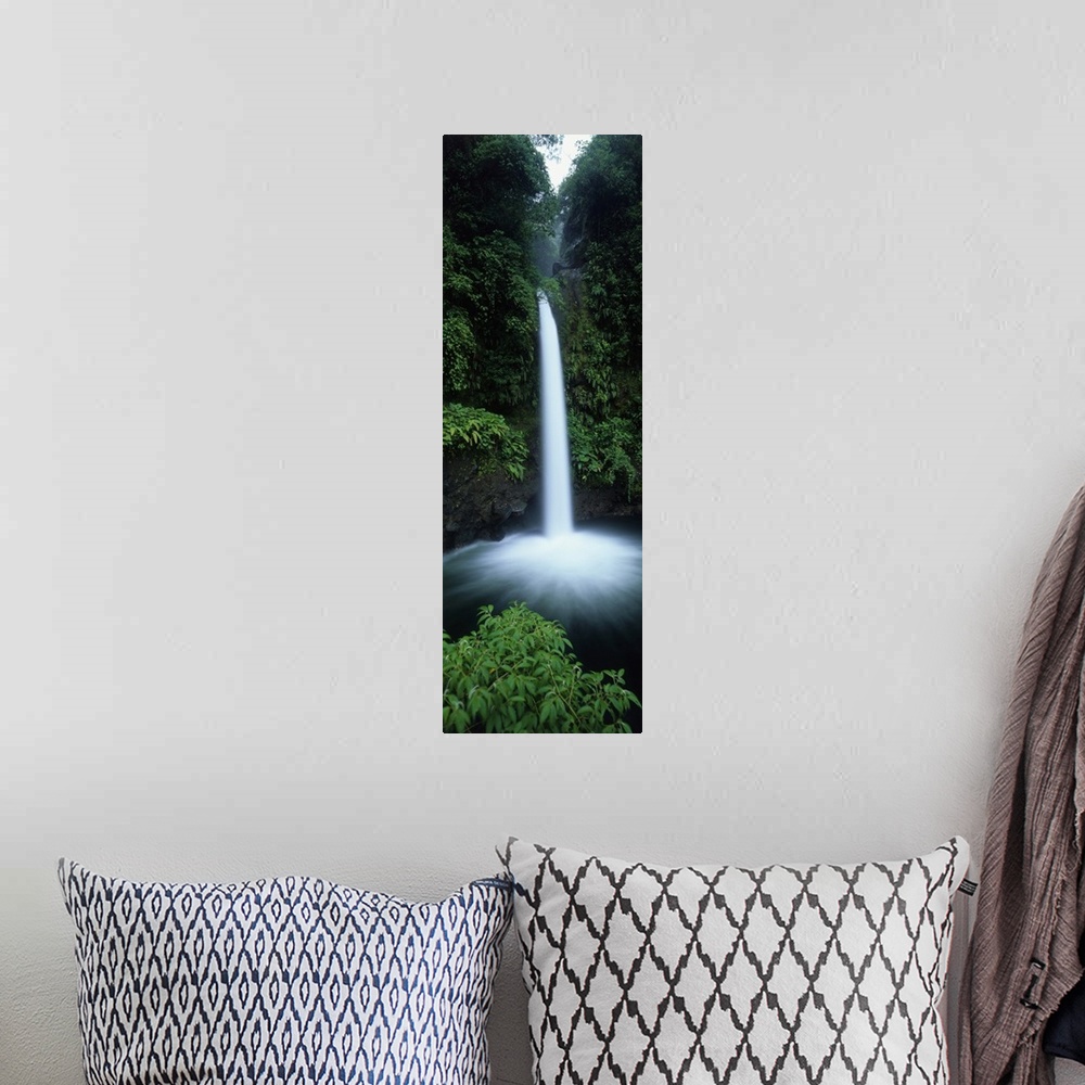 A bohemian room featuring Vertical canvas print of a narrow but powerful waterfall rushing down from a tropical forest.