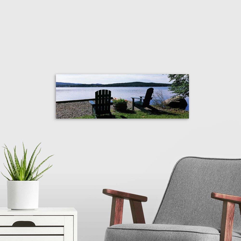 A modern room featuring A panoramic photograph of Adirondack chairs arranged with a view of a lake on a bright sunny day.