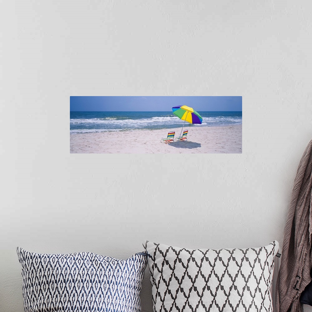 A bohemian room featuring Panoramic photograph includes two chairs sitting under a vibrantly colored umbrella as the waves ...