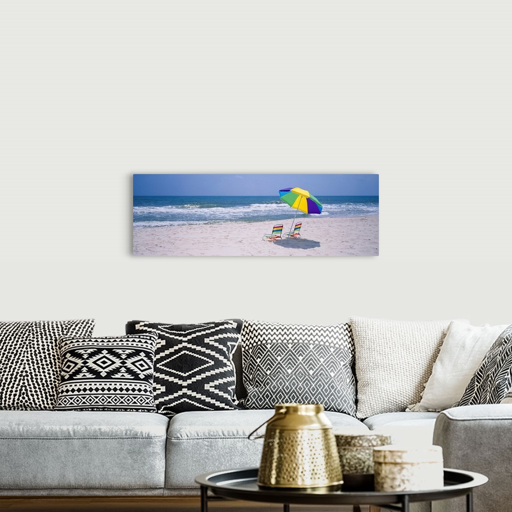 A bohemian room featuring Panoramic photograph includes two chairs sitting under a vibrantly colored umbrella as the waves ...