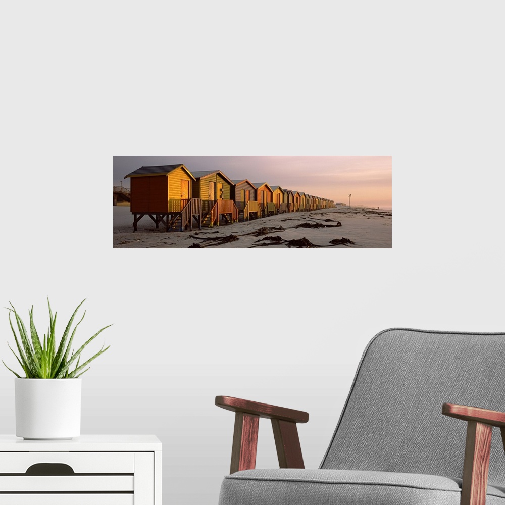 A modern room featuring A panoramic photograph of a row of buildings built on the sandy shoreline glowing in the light of...
