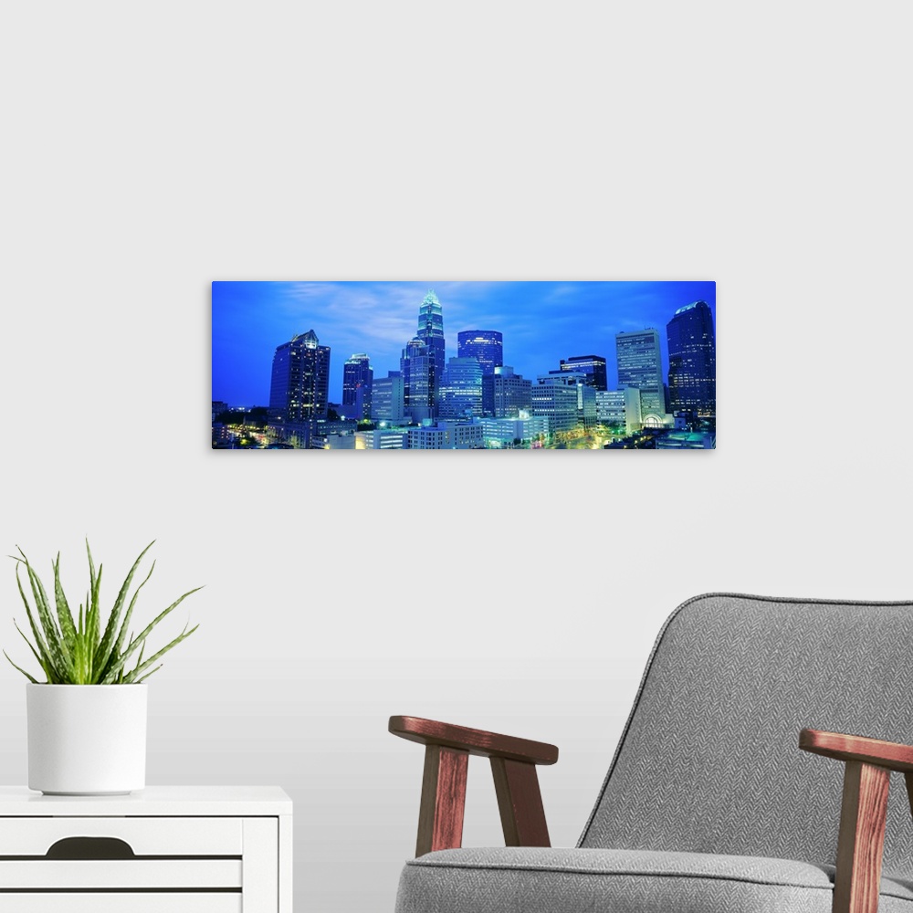 A modern room featuring Giant, panoramic photograph of the Charlotte skyline at night.