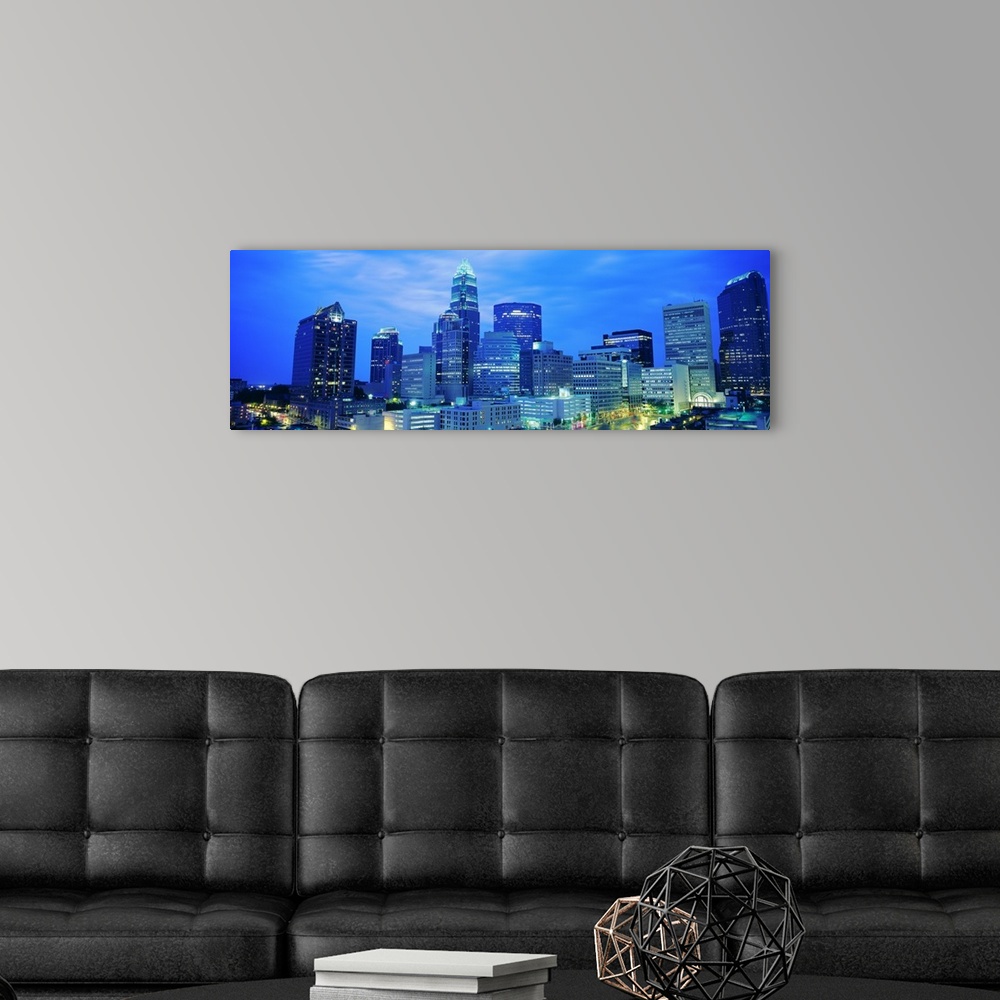 A modern room featuring Giant, panoramic photograph of the Charlotte skyline at night.