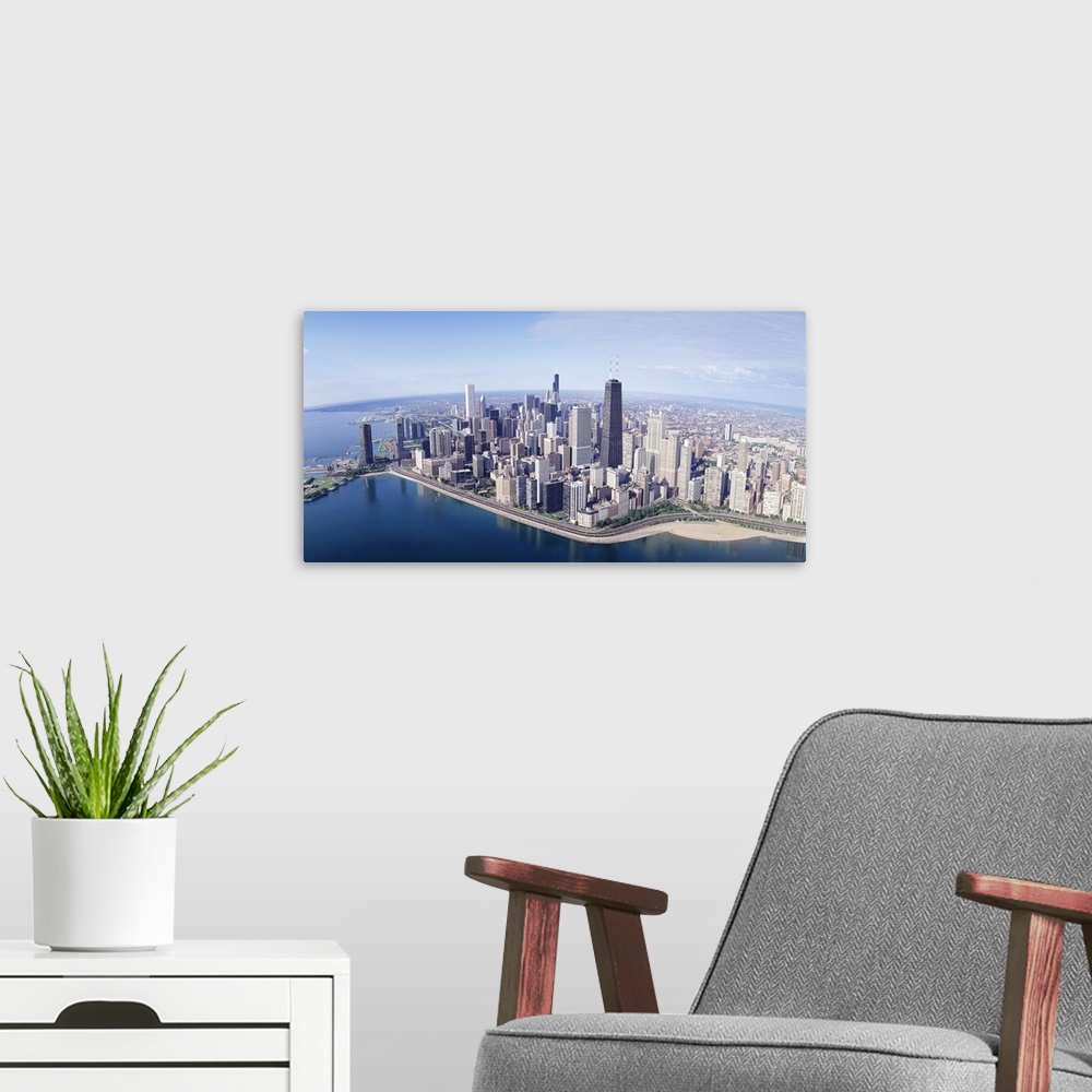 A modern room featuring Large, landscape aerial photograph of the large city of Chicago, Illinois, surrounded by calm blu...