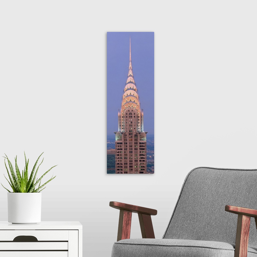 A modern room featuring Lit up spire and top floors of the Chrysler building at dusk.