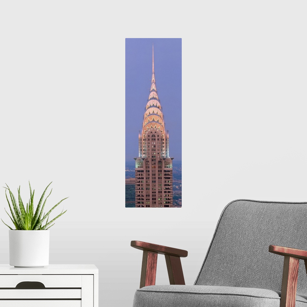 A modern room featuring Lit up spire and top floors of the Chrysler building at dusk.