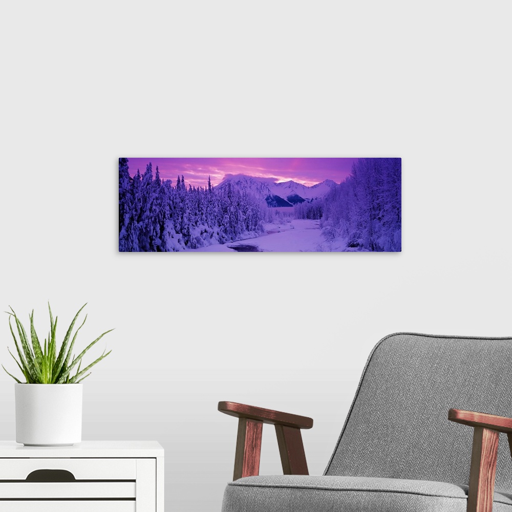 A modern room featuring Panoramic photo art of snow covered forests on the left and right of a snowy open space with a su...