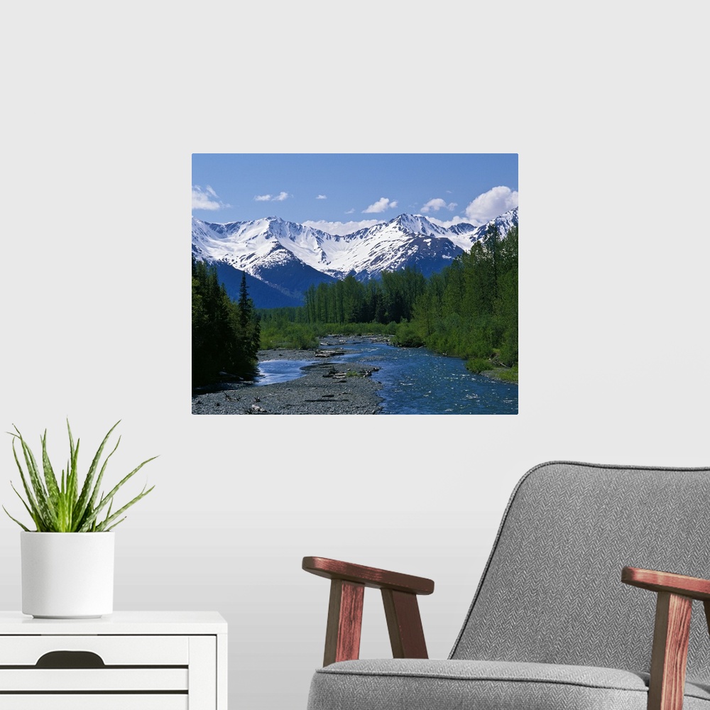 A modern room featuring Large photograph of a stream running through a forest with the snowy Chugach Mountains in Alaska ...