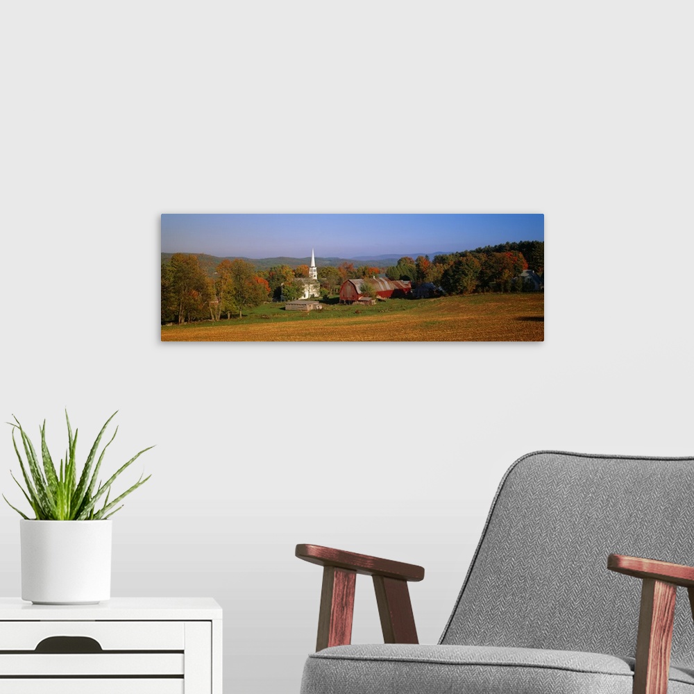 A modern room featuring This panoramic photograph is of a barn and a church surrounded by autumn trees with large hills i...