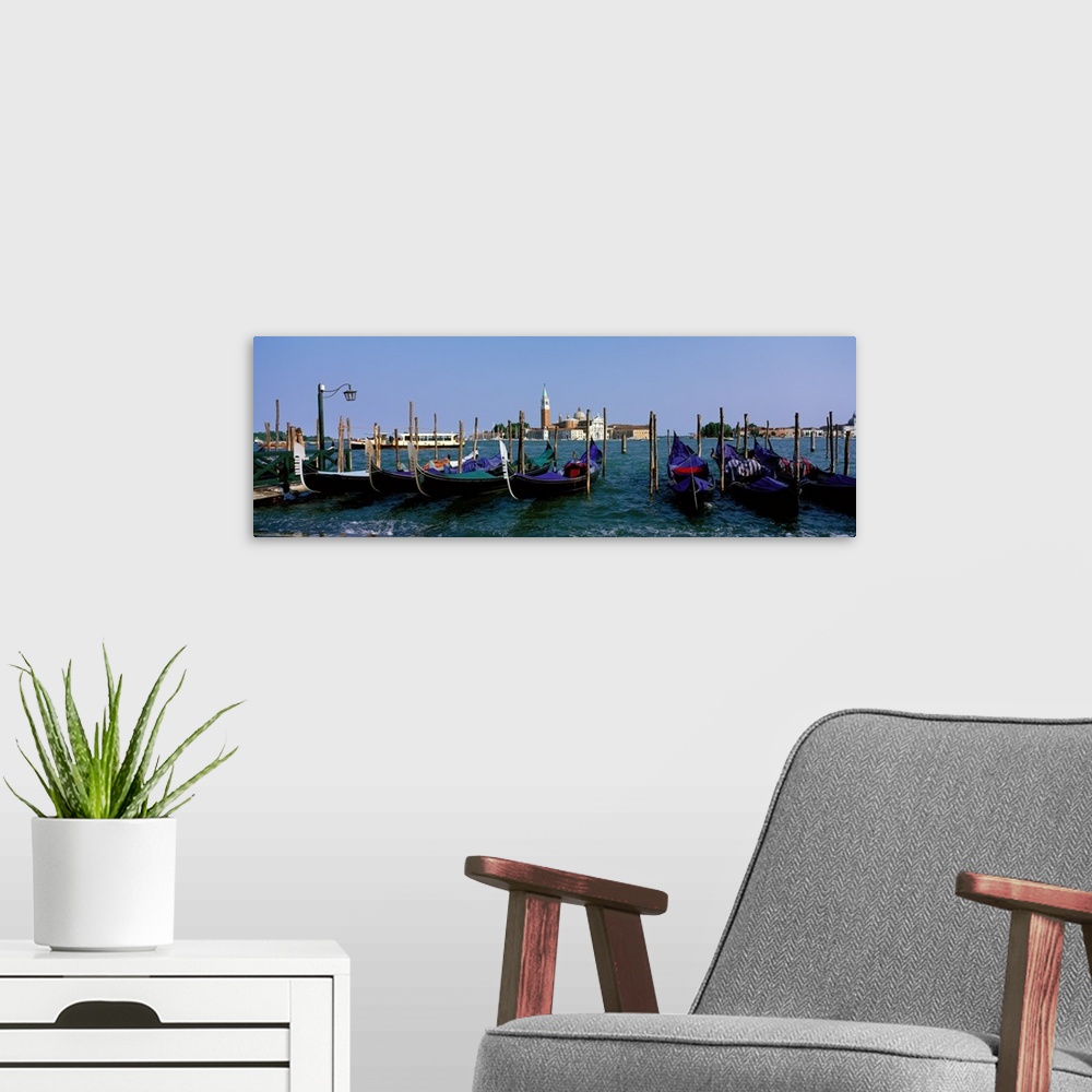 A modern room featuring Long photo on canvas of gondolas parked  near posts in Italy.