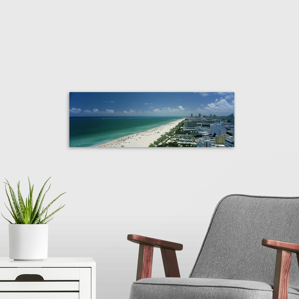 A modern room featuring An aerial photograph is taken of the coast in Miami showing a busy beach lined by the teal ocean ...
