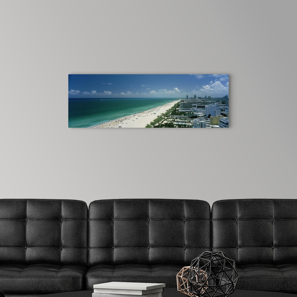 A modern room featuring An aerial photograph is taken of the coast in Miami showing a busy beach lined by the teal ocean ...