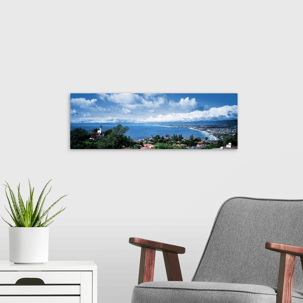 A modern room featuring Large panoramic print of a city along the Pacific Ocean with big billowing clouds in the distance.