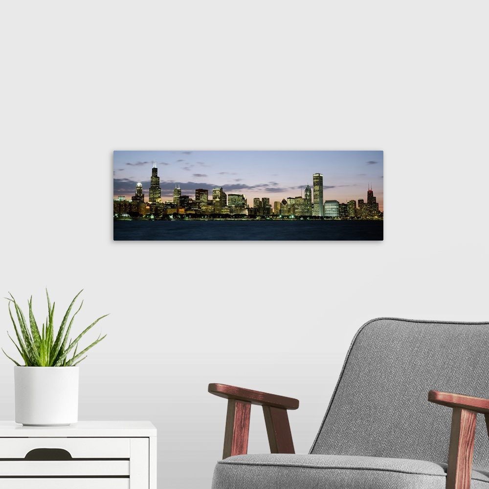 A modern room featuring Panoramic photograph displays a horizon filled with tall skyscrapers and buildings as the sun beg...