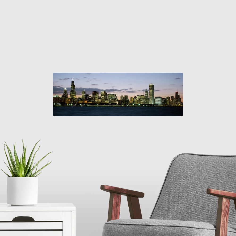 A modern room featuring Panoramic photograph displays a horizon filled with tall skyscrapers and buildings as the sun beg...