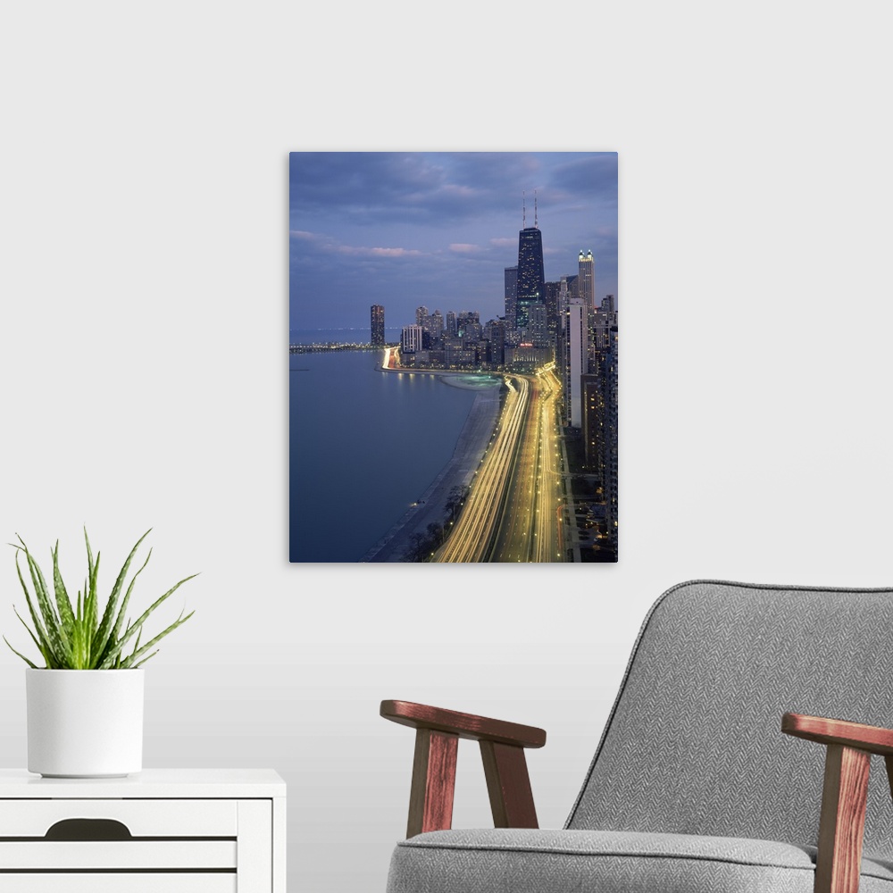A modern room featuring Vertical panoramic photograph at dusk with city skyline in the distance and busy highway and stre...