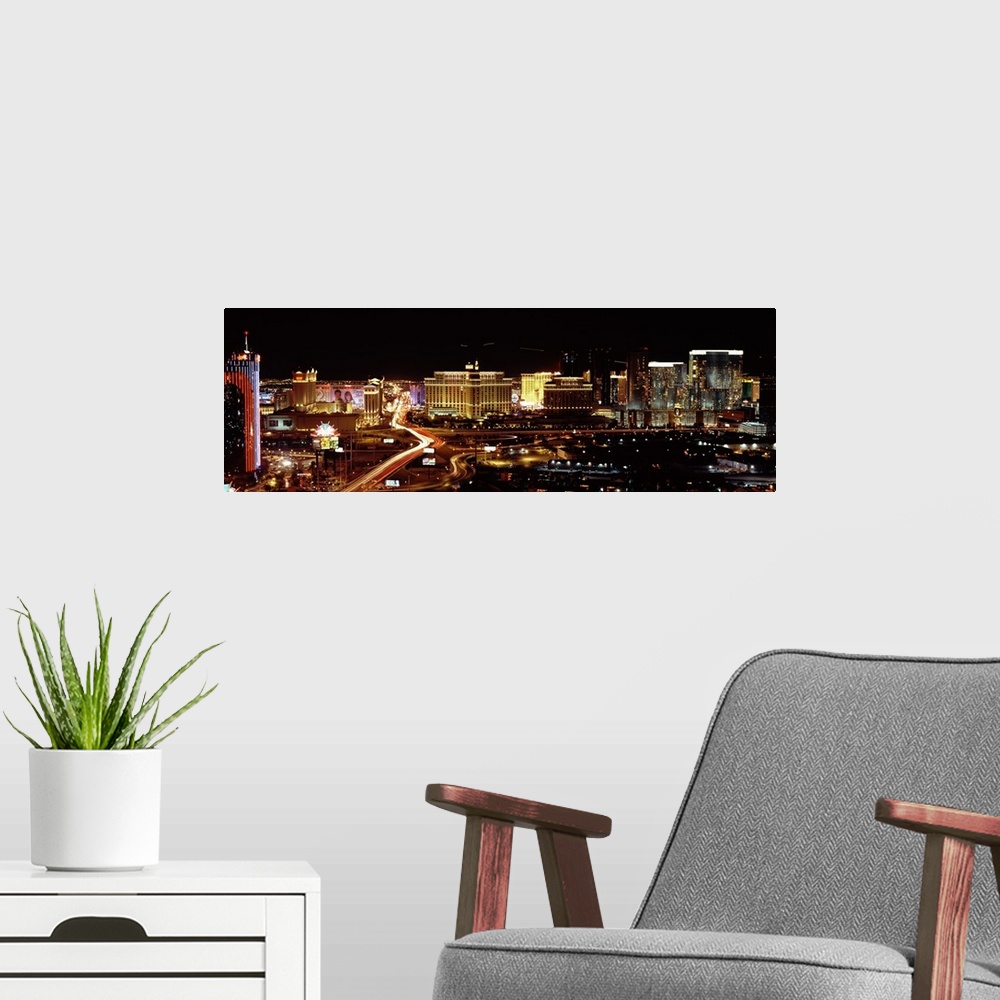 A modern room featuring A time lapsed photograph of a car lights streaming through the city road ways with the all the li...