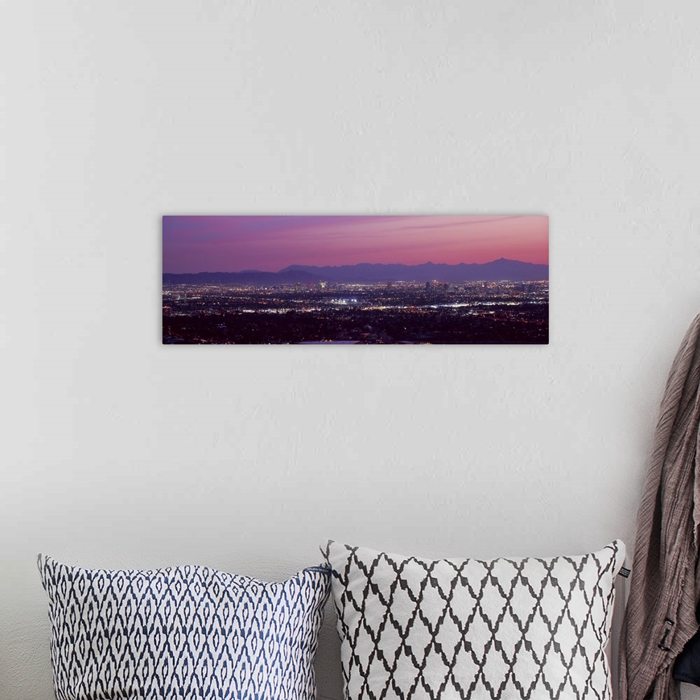 A bohemian room featuring The city of Phoenix is illuminated under a dusk sky and shot in a panoramic view to show majority...