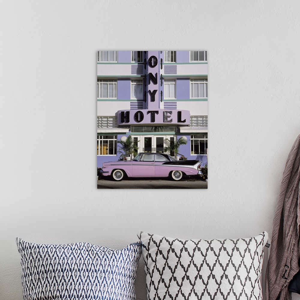 A bohemian room featuring Vertical photograph on a large wall hanging of an old, classic car parked beneath the sign for th...