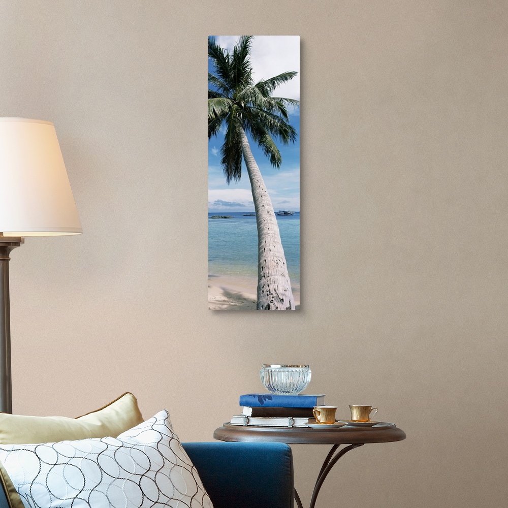 A traditional room featuring A vertical, panoramic shaped canvas of a single tree in front of a tropical ocean and anchored boat.