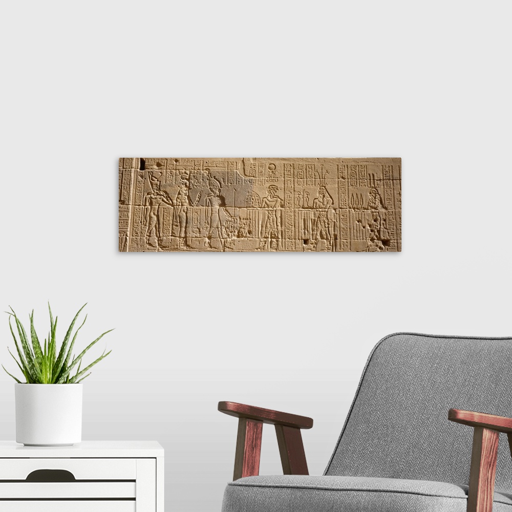 A modern room featuring Wide photo on canvas of Egyptian hieroglyphics carved into a rock wall.