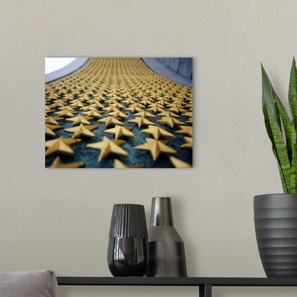 A modern room featuring Small golden stars are attached onto a large wall at a war memorial in the countries capital.