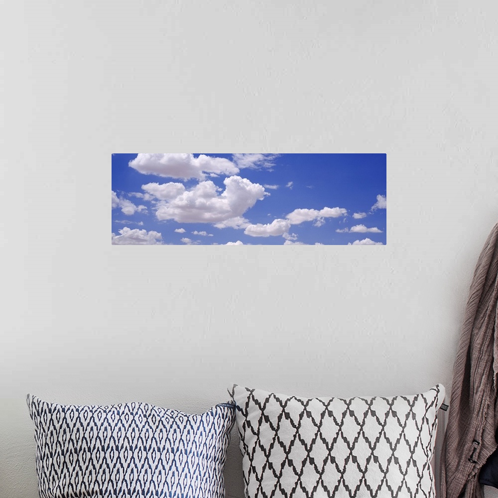 A bohemian room featuring Giant, landscape photograph of a light blue sky with large, fluffy, white clouds.