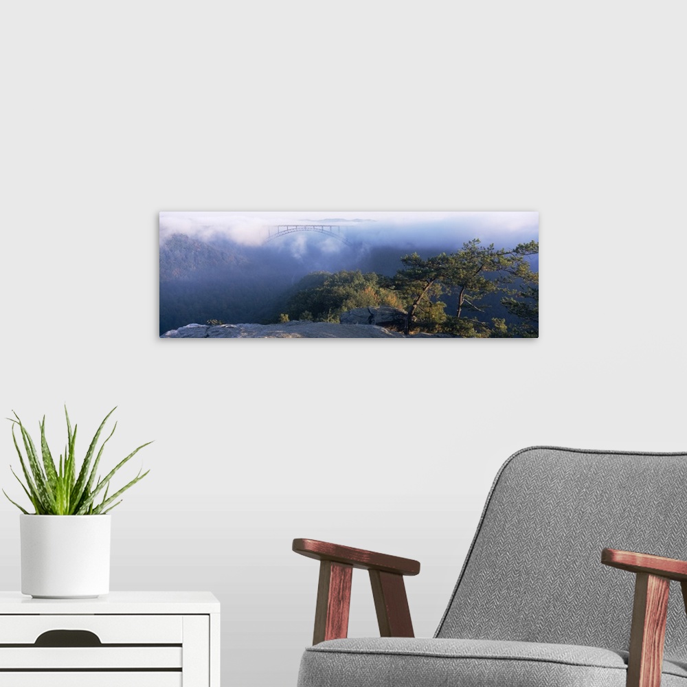 A modern room featuring Panoramic image of the new River Gorge Bridge peeking through the fog high above the New River an...