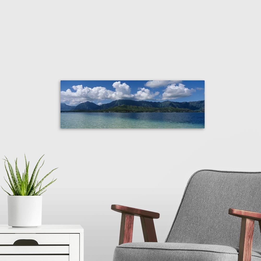 A modern room featuring Panoramic photograph taken across the ocean looking at a Hawaiian island with immense clouds floa...